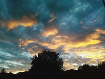 Low angle view of silhouette trees against dramatic sky