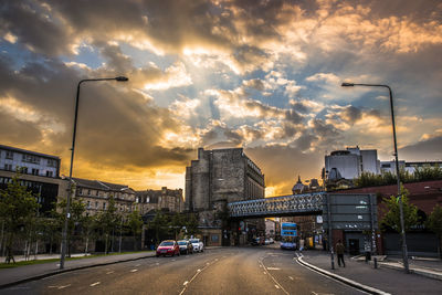 Cars on road against cloudy sky