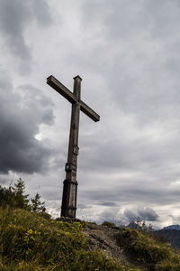 Low angle view of cross on field against sky