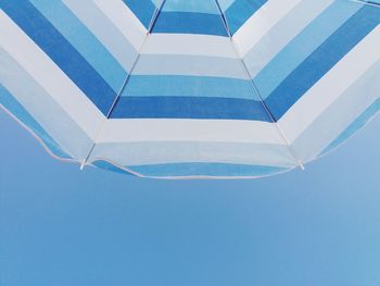 Low angle view of umbrella against clear blue sky