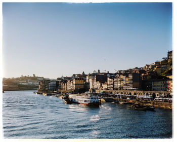 City buildings by sea against clear sky