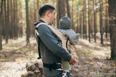 Side view of young man standing in forest