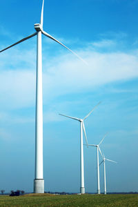 Windmills on field against sky