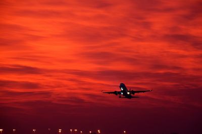 Low angle view of silhouette airplane against sky during sunset