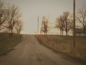 Road amidst bare trees against sky