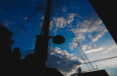 Low angle view of power lines against cloudy sky