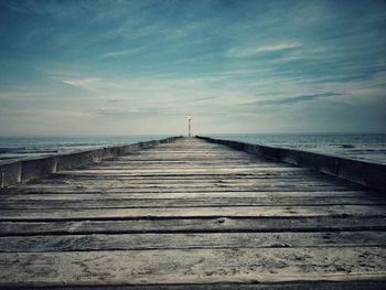 Pier on sea against cloudy sky