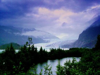 Scenic view of lake and mountains against cloudy sky