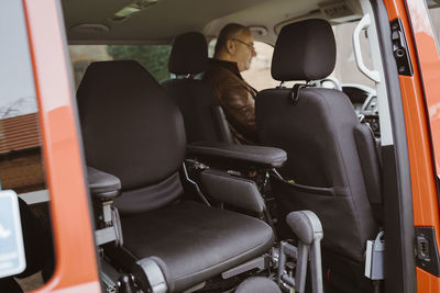 Motorized wheelchair against man with disability sitting in van