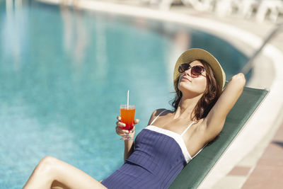 Midsection of woman drinking water in swimming pool