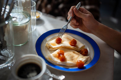 Man having tasty breakfast in restaurant pancakes with jam from apples ranets.