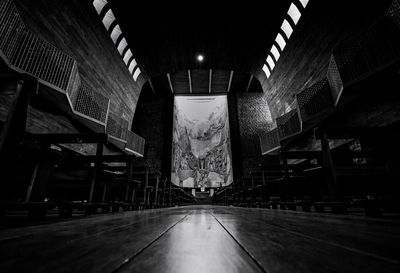 Perspective view in church. a few people sit on wooden bench with many of empty bench in church.