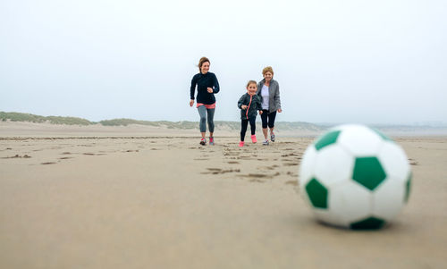 Happy family playing with ball at beach