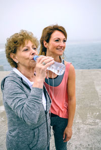 Woman with mother standing on pier against sky