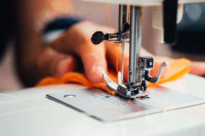 Cropped hand of woman using sewing machine at workshop