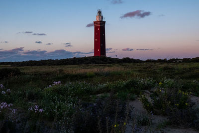 Lighthouse standing on the dutch coast with a dramatic. and colorful dusk or dawn sky behind it