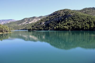 Scenic view of lake and mountains against clear blue sky