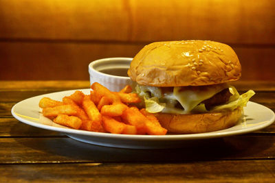 Close-up of burger and french fries served in plate on table