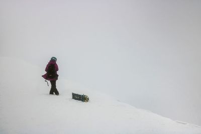 Rear view of person walking on snow covered land