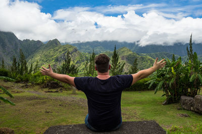 Rear view of man with arms outstretched looking at mountains