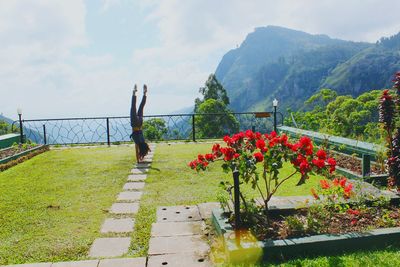 Woman doing handstand at observation point by mountain against sky