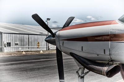 Close-up of airplane on airport runway against sky