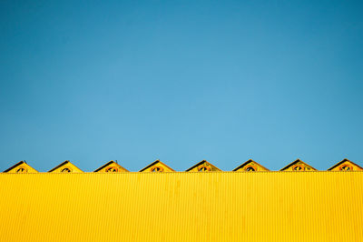 Low angle view of yellow built structure against clear blue sky