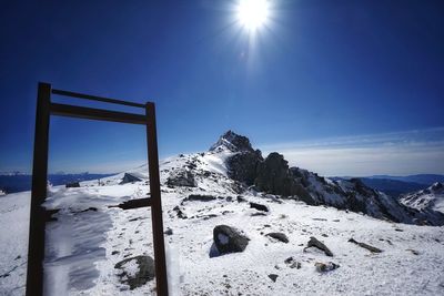 Scenic view of snowcapped mountains against blue sky on sunny day