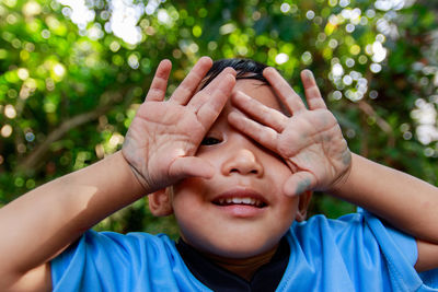 Close-up of boy covering eyes with hands