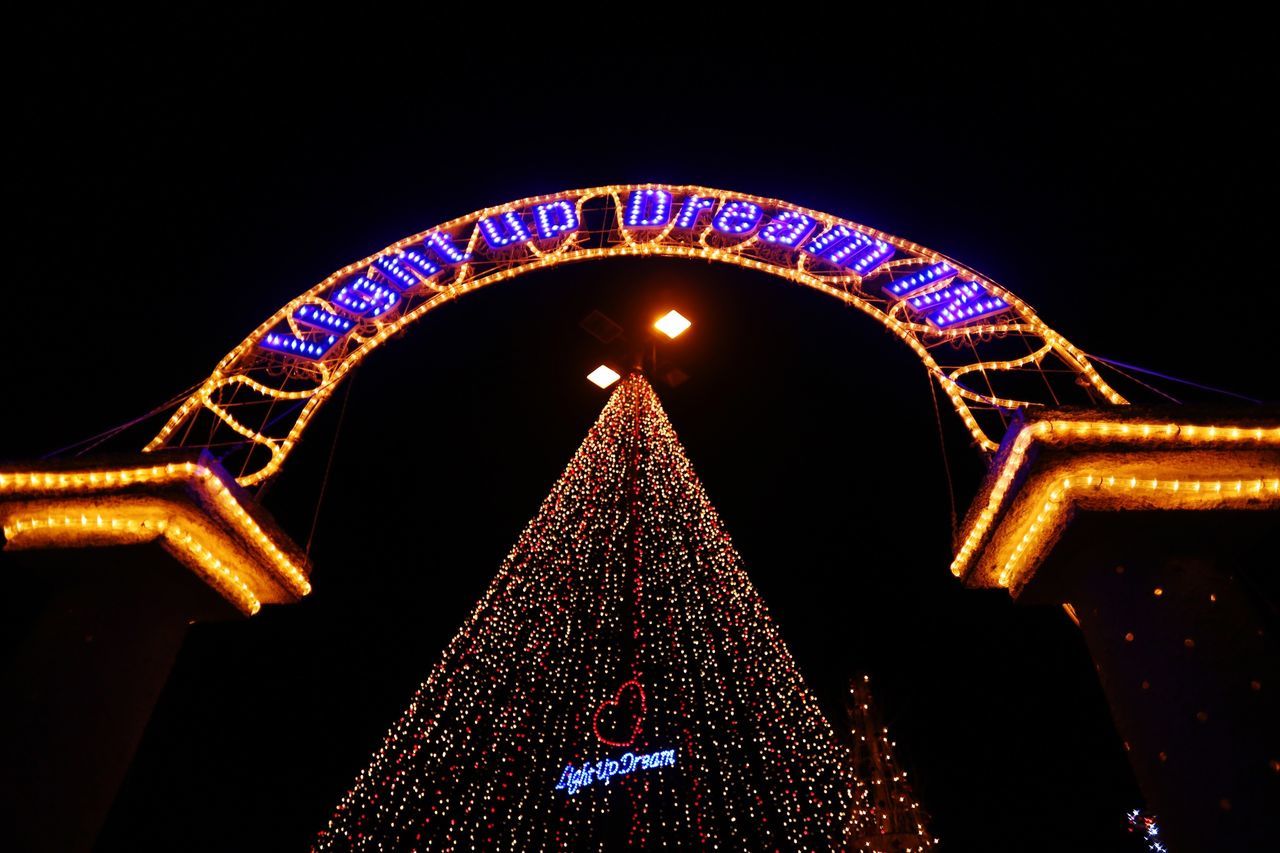 illuminated, night, arts culture and entertainment, ferris wheel, amusement park ride, low angle view, amusement park, architecture, built structure, famous place, travel destinations, clear sky, tourism, capital cities, international landmark, sky, travel, lighting equipment, city, multi colored