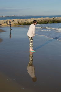 Side view of siblings standing at beach against sky