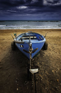 Boat moored on beach against sky