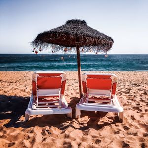 Deck chairs on beach against clear sky