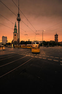 Cars on road in city against sky during sunset