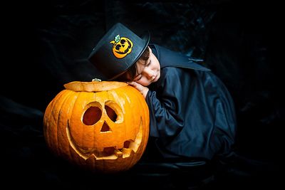 Full length of a man standing by pumpkin against black background