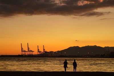 Silhouette people on pier by sea against sky during sunset