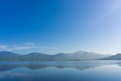 Scenic view of lake and mountains against blue sky