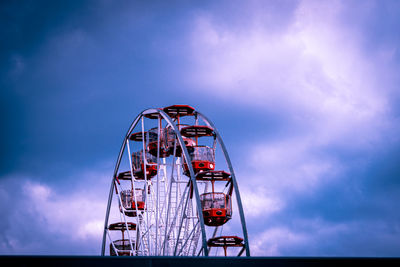 Low angle view of ferris wheel against cloudy sky