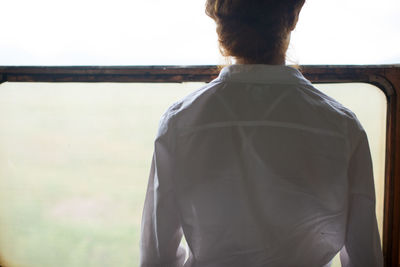 Rear view of woman looking through window in train