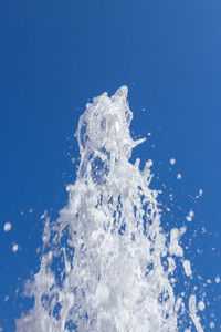Close-up of spraying water against clear blue sky