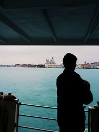 Rear view of man standing on boat in sea