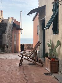 Potted plants and deck chairs by sea against buildings