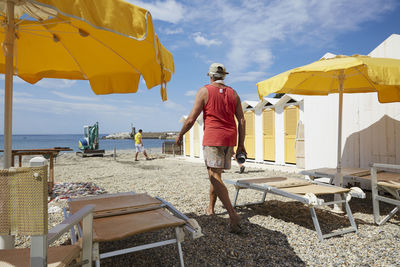 Rear view of man standing on beach against sky