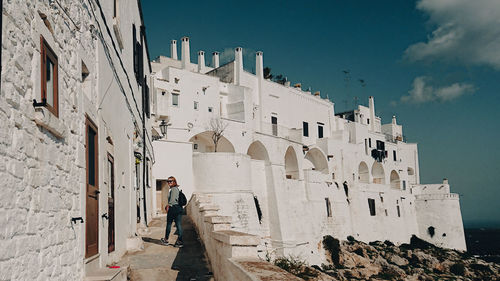 Man standing by old building against sky