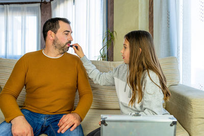 Girl applying lipstick to father at home