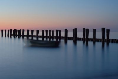 Wooden posts in sea against clear sky