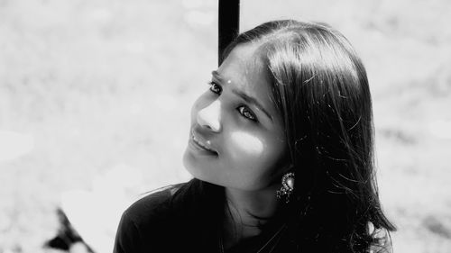 Close-up portrait of young woman looking away outdoors