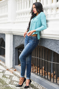 Full length of thoughtful woman standing against wall