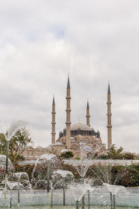 Fountain in front of building against sky