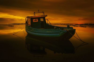 Boat moored in sea against sky during sunset